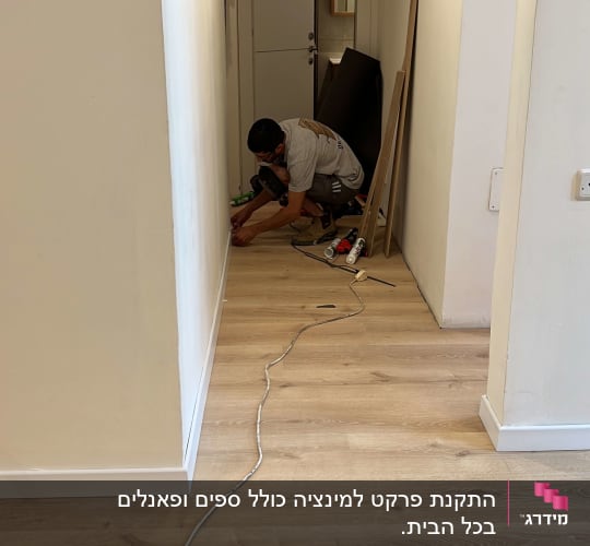 אדם מתקין פרקט בעזרת כלים בחדר צר